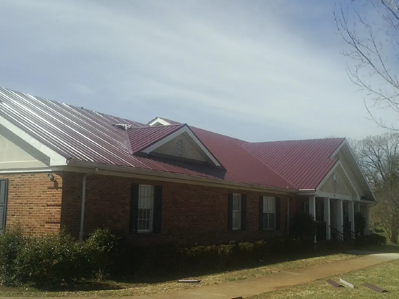 Red metal roof with gabled entries on a long brick building in Drewsville