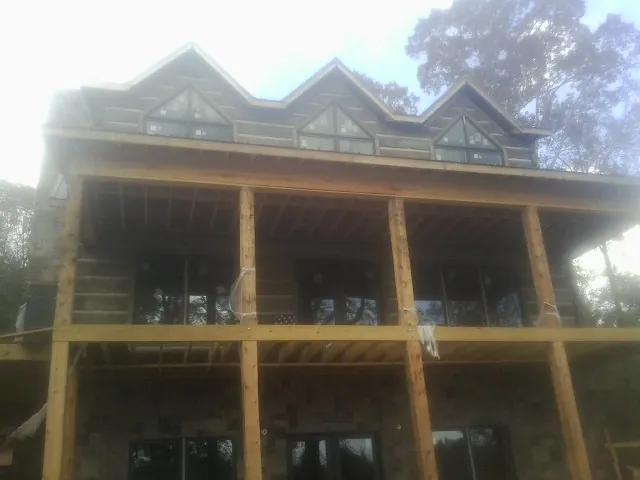 Dormers and porch framing on a large log home under construction — Roof Coating work by our crew in Drewsville