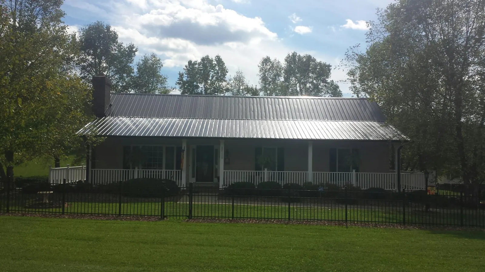 Gray metal roof on a brick ranch with a full width front porch — Gutter Guard Installation work by our crew in Drewsville