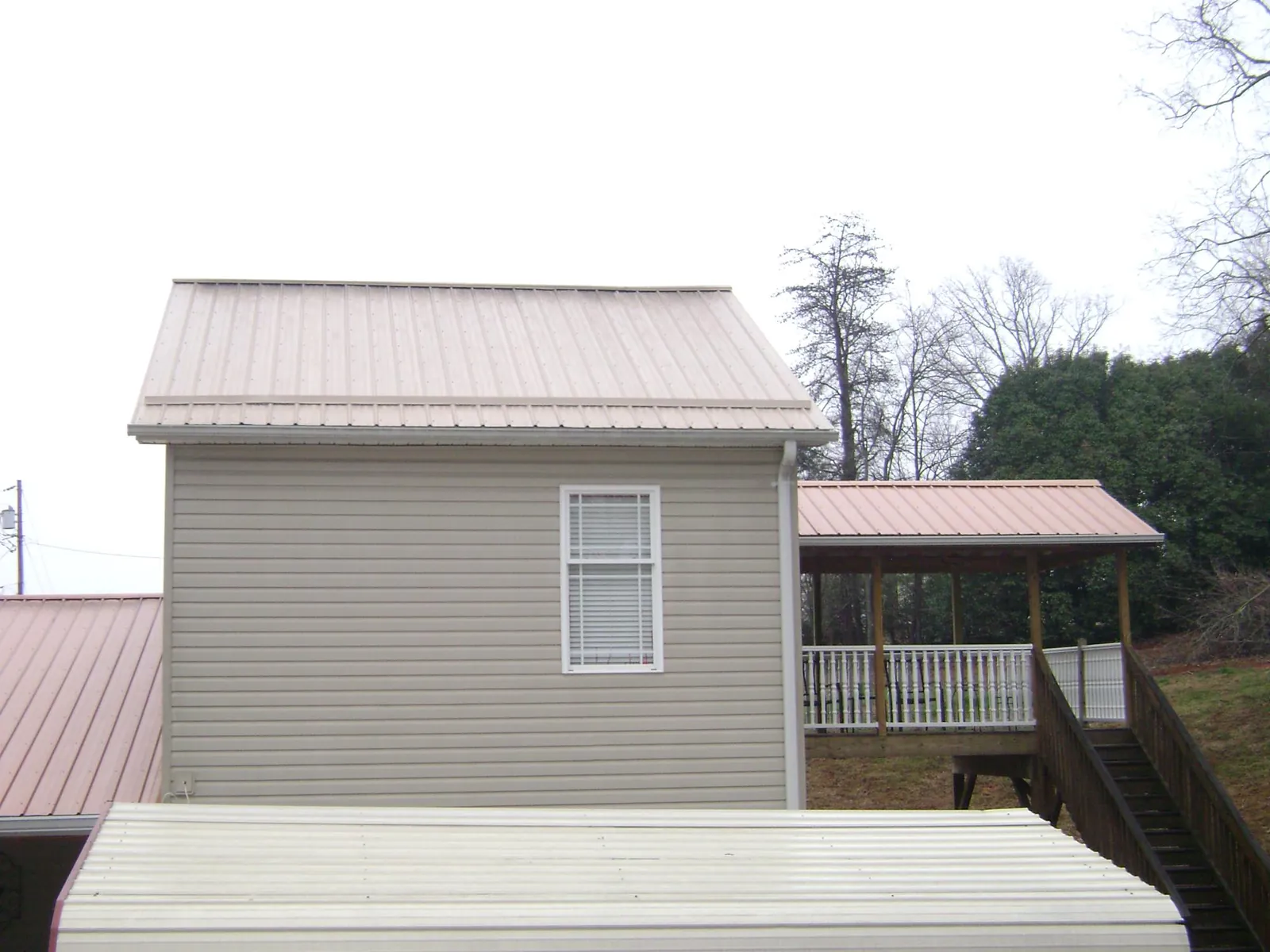 Tan metal roofs on a two story addition and attached porch, from a Roof Replacement job in Drewsville