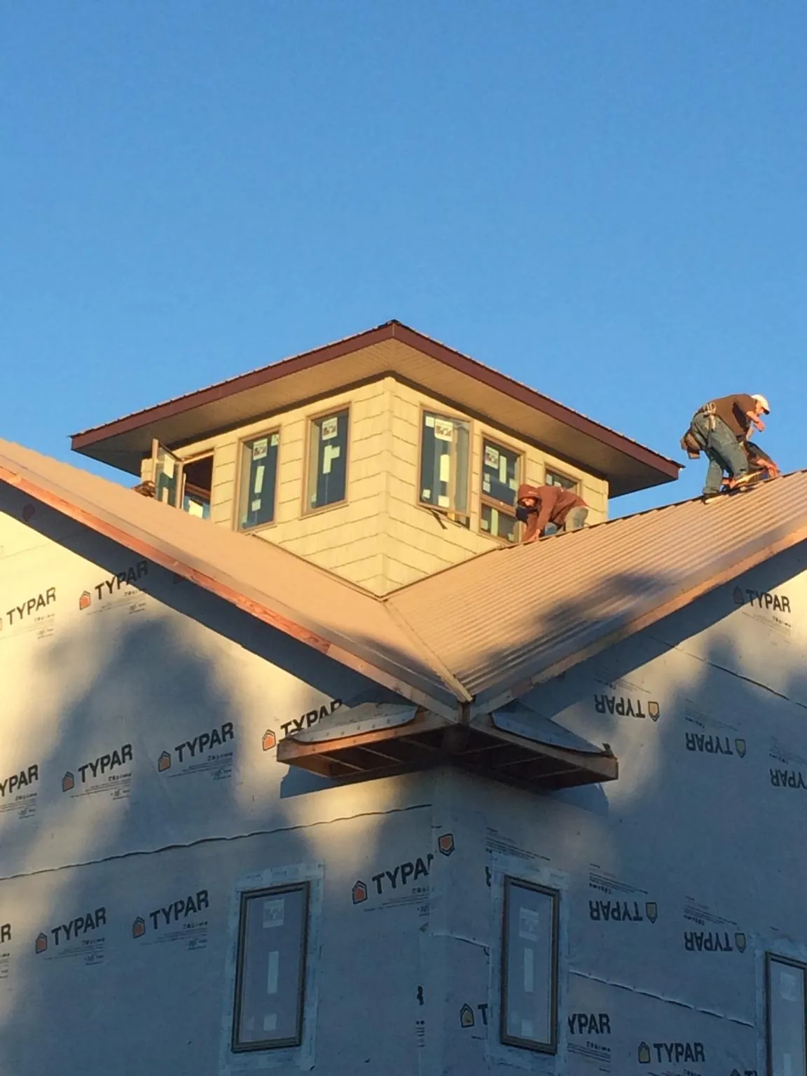 Roofers working around a rooftop cupola on a new metal roof at sunset — Roof Waterproofing in Drewsville by Roofing Brothers